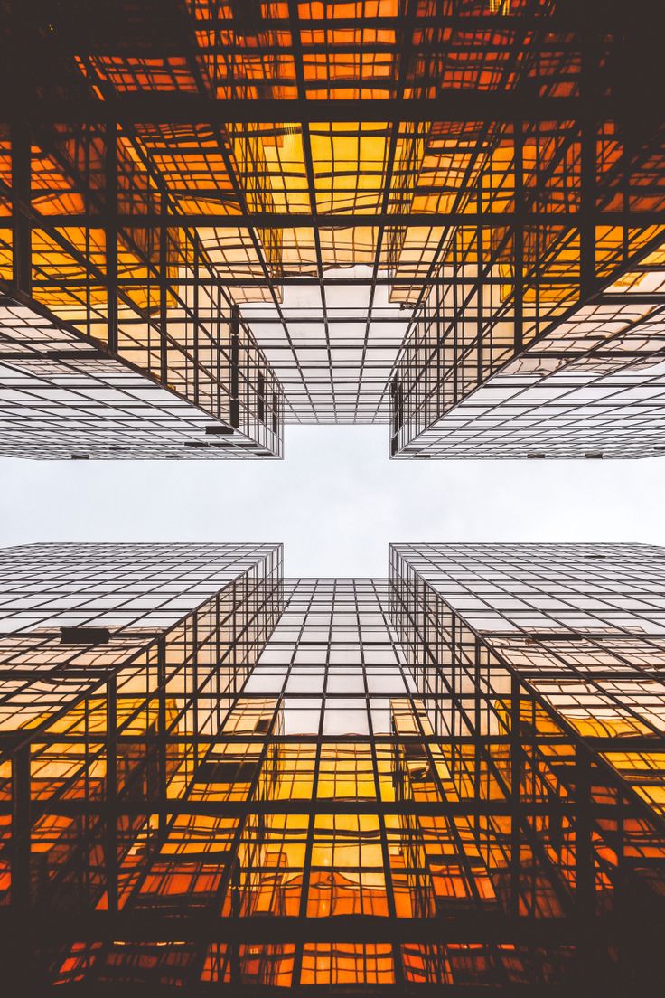 looking up at the sky through an abstract building's glass and steel facades