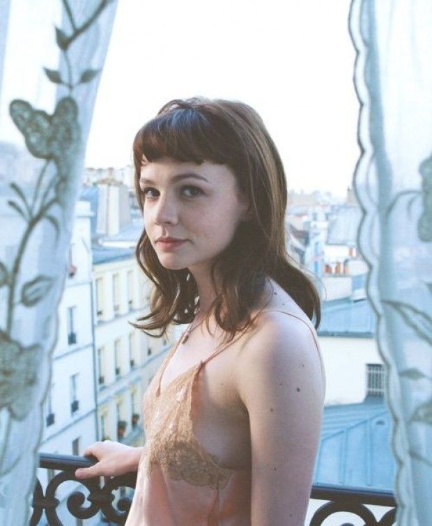 a woman standing in front of a window next to a balcony with curtains on it