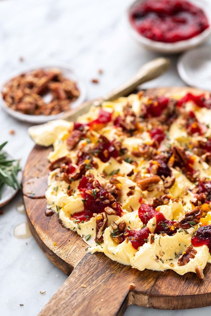 a pizza sitting on top of a wooden cutting board next to other food and utensils