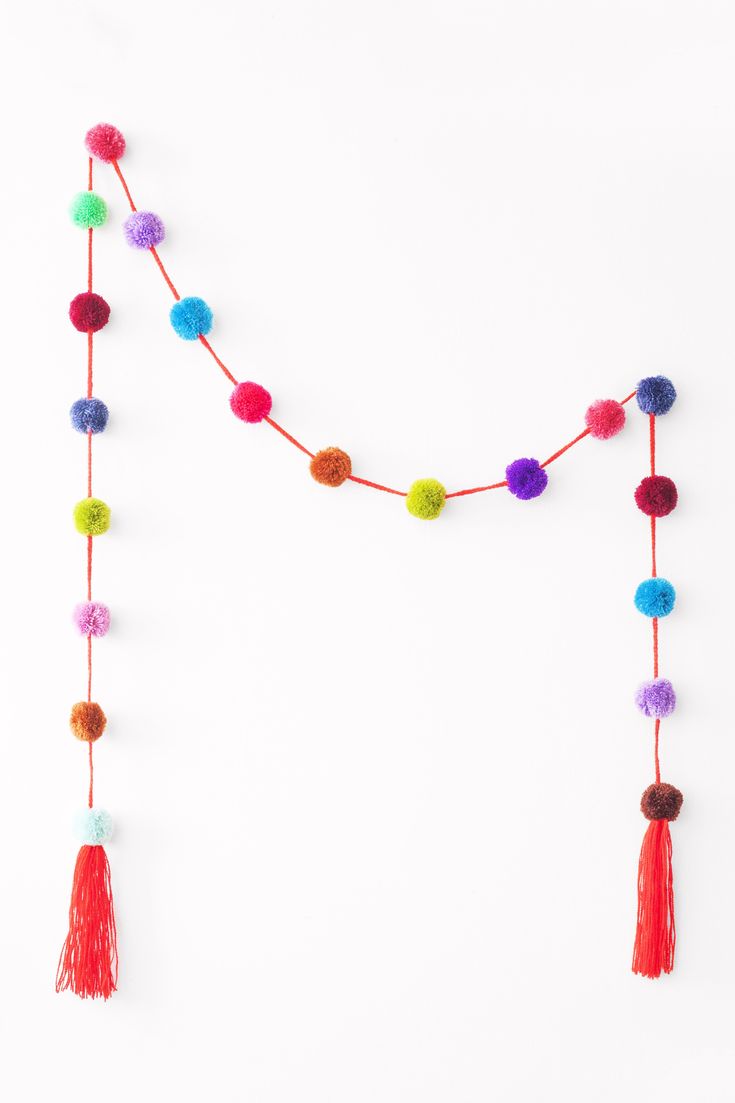 multicolored pom - pom garland with tassels on white background