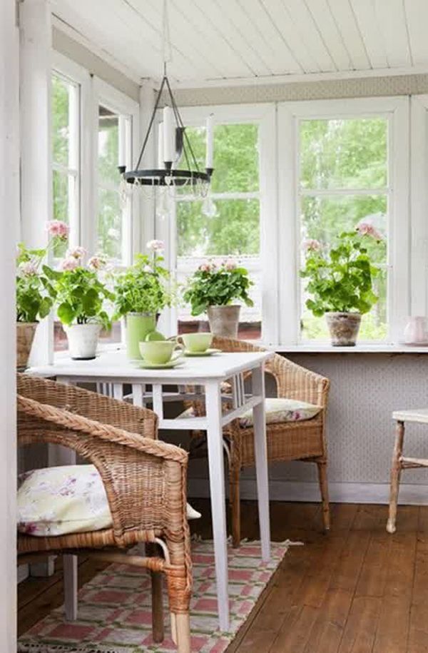 an image of a small sunroom with plants on the window sill and chairs