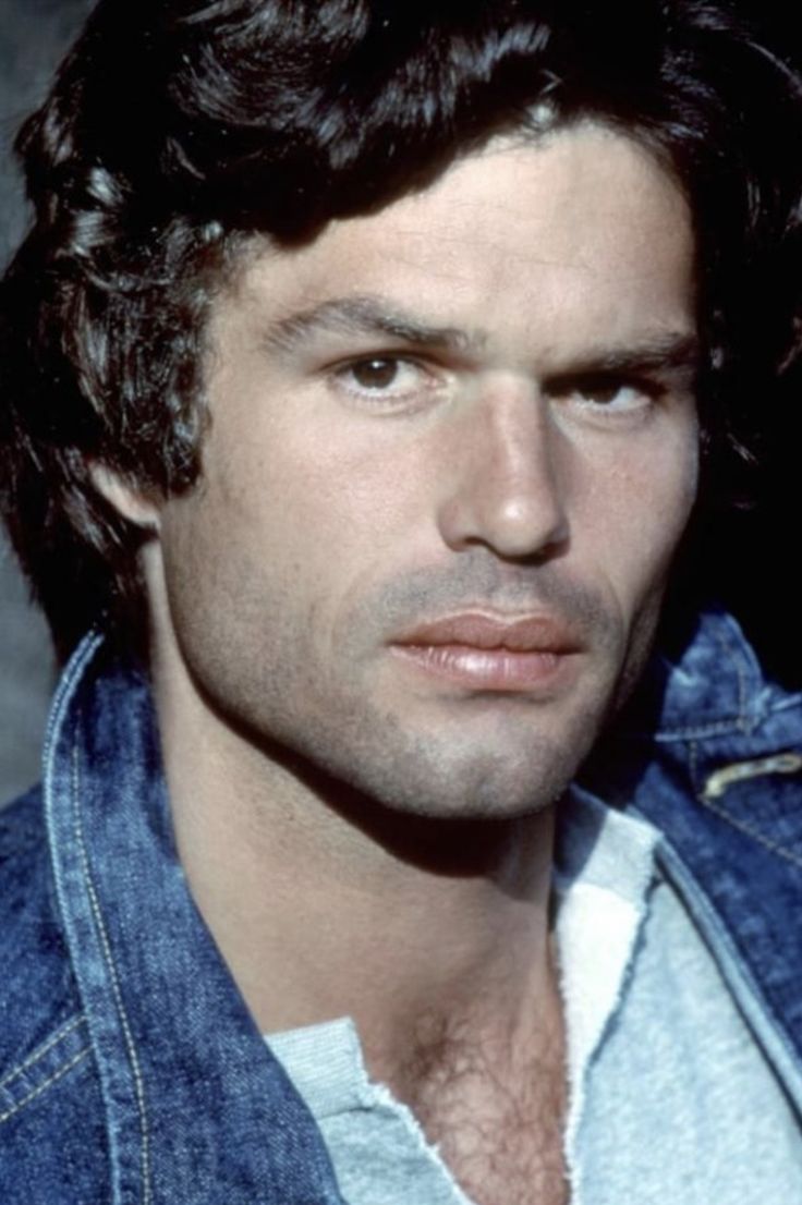 a close up of a person wearing a denim jacket and looking at the camera with a serious look on his face