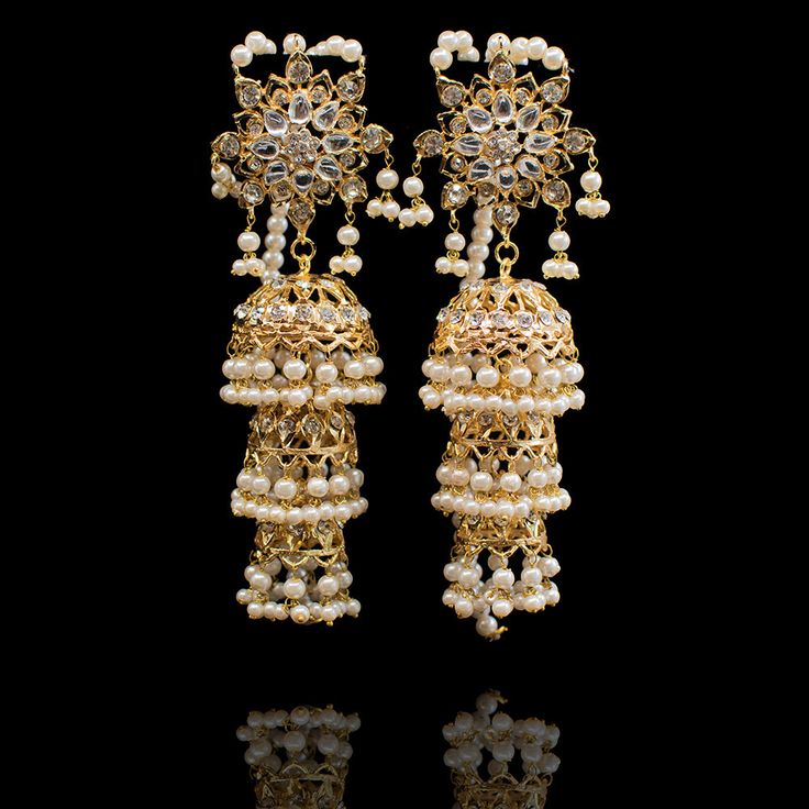 Perfect when you are looking to make a glorious and a majestic impact! Dreamy pair of earrings encrusted with CZ stones and laced with white pearl moti. Approximate earrings length is 4.5". Gold-plated on high-quality brass as the base metal. In-stock & ready-to-ship. *Please Note: We use faux stones and beads in all of our jewelry. Ornate White Pearl Drop Earrings, White Chandbali Pearl Earrings For Reception, Fusion Style Party Chandelier Earrings With Stone Work, Heavy White Chandelier Earrings For Festive Occasions, White Bridal Earrings With Intricate Design For Celebration, Festive Bridal Earrings With Intricate Metal Design, White Kundan Chandelier Earrings For Receptions, White Chandbali Chandelier Earrings For Reception, Elegant Heavy Bridal Earrings In Brass