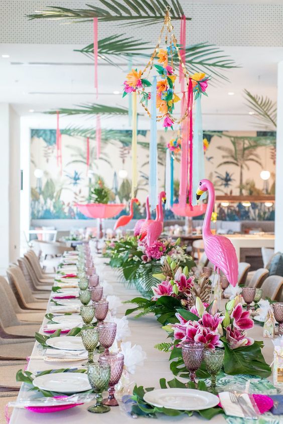 the table is set with pink flamingos and tropical flowers