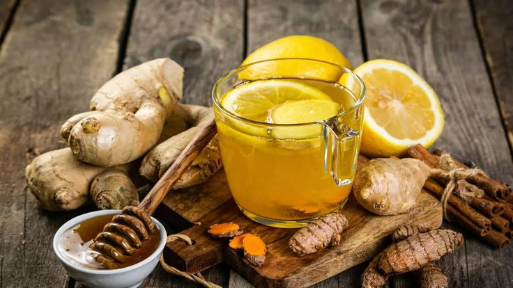 a glass mug filled with liquid next to sliced lemons and ginger