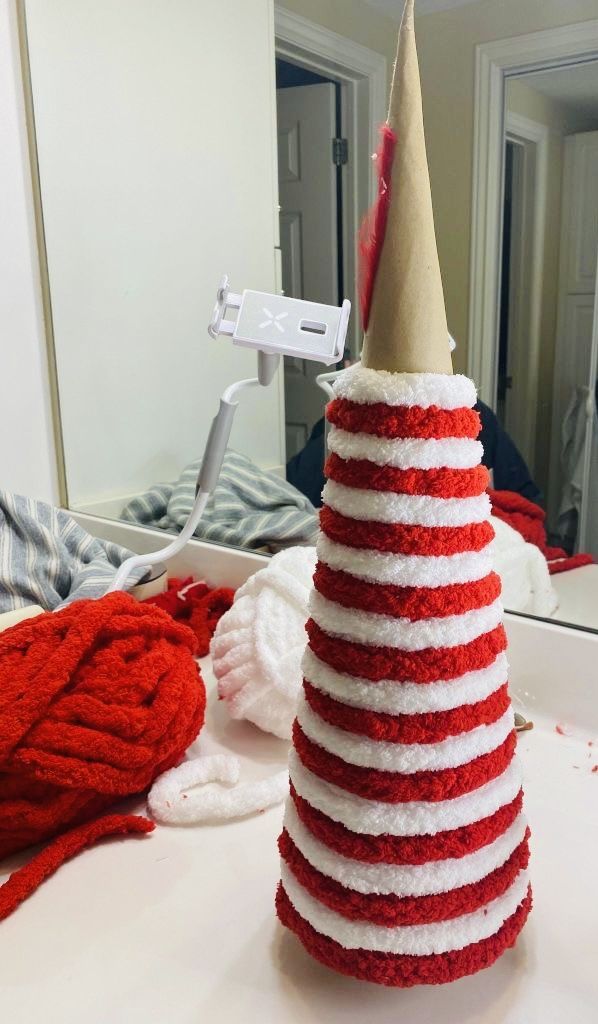 a red, white and blue knitted christmas tree sits on a table in front of a mirror