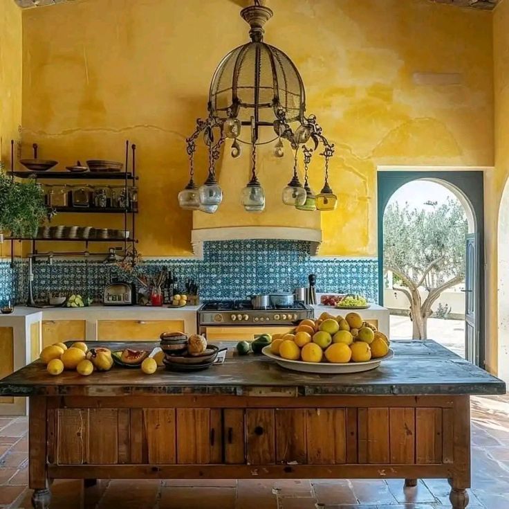 a kitchen with yellow walls and an island in front of the counter top filled with fruit