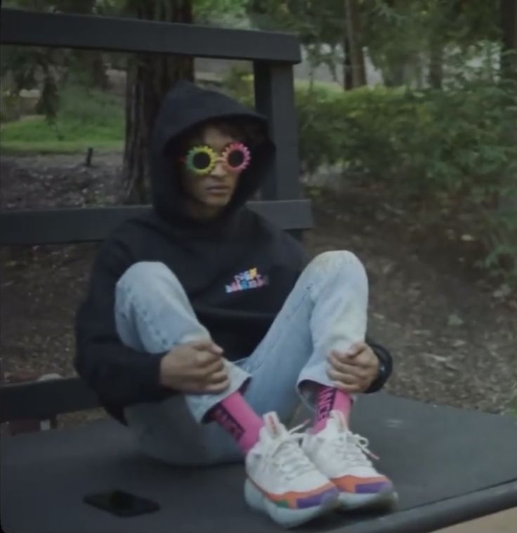 a person sitting on a bench with their feet up and wearing sunglasses that are pink