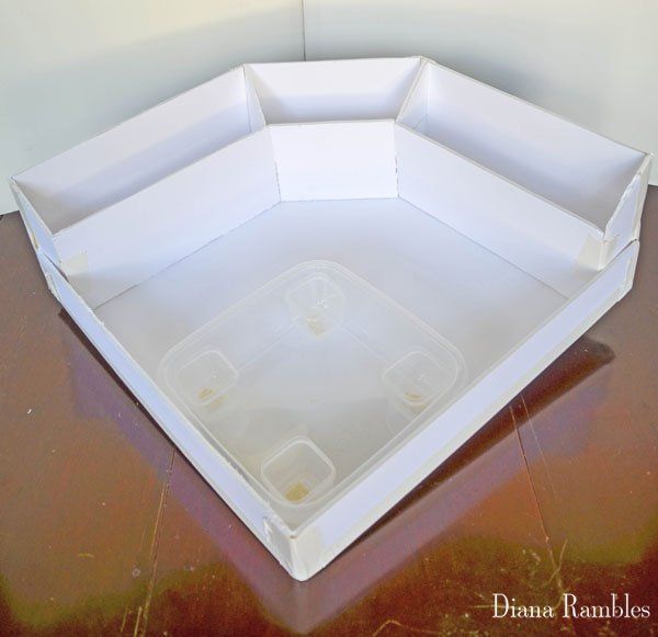 an empty white box sitting on top of a wooden table next to a brown wall