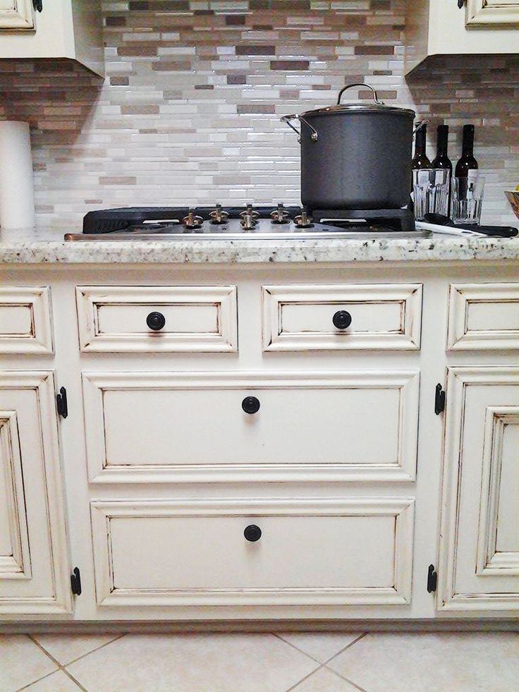 a kitchen with white cabinets and black knobs