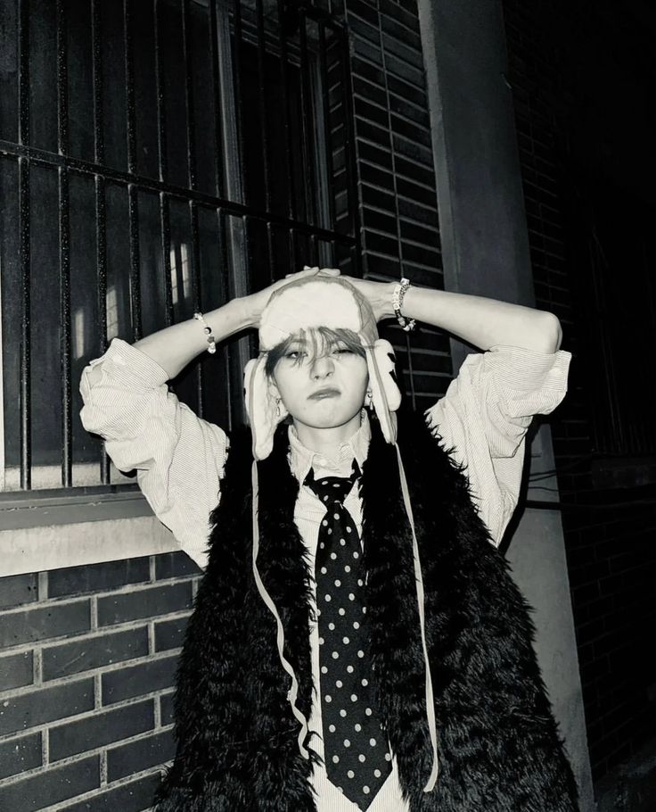 black and white photograph of a woman with her hands on her head wearing a tie