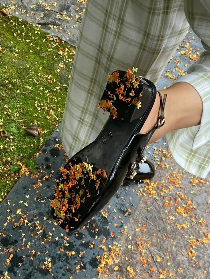 a person standing on the ground with their shoes covered in autumn leaves and falling petals