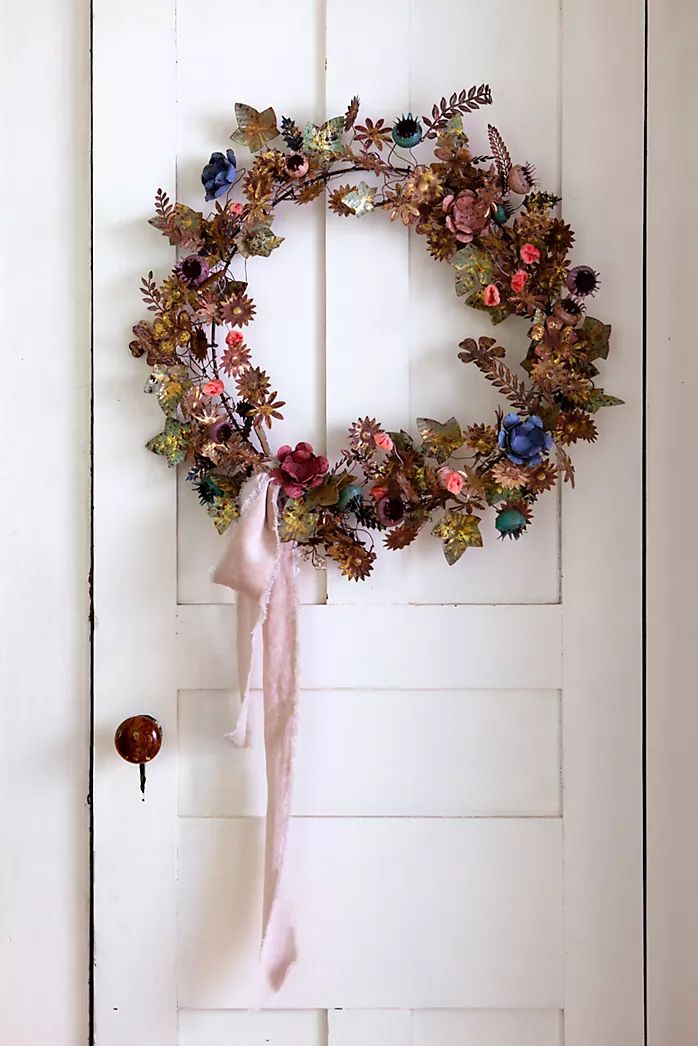 a wreath is hanging on the door with a pink ribbon and some other decorations around it