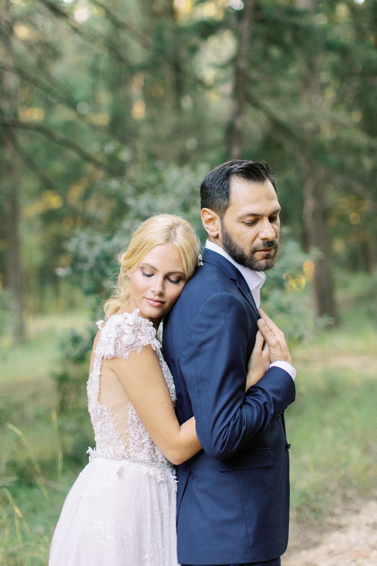 a bride and groom embracing in the woods