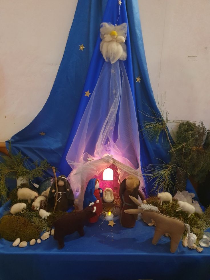 a blue table topped with figurines and a lit up nativity scene on top of it