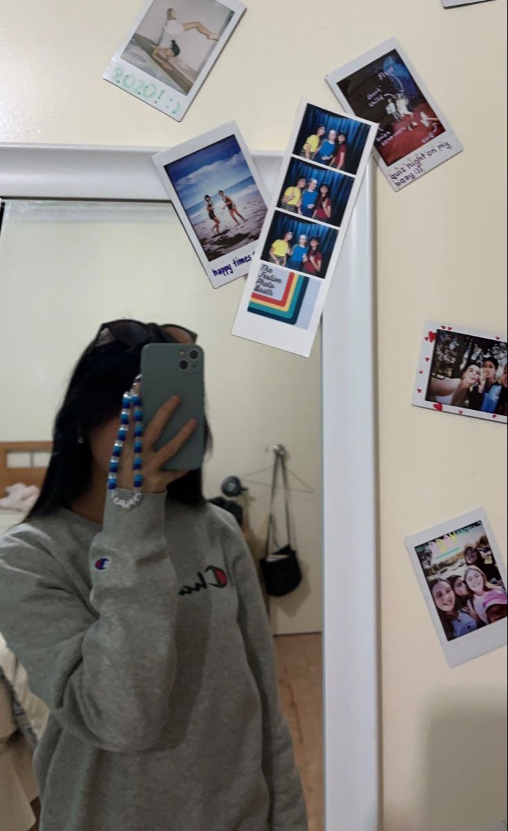 a woman taking a selfie in front of a mirror with pictures on the wall