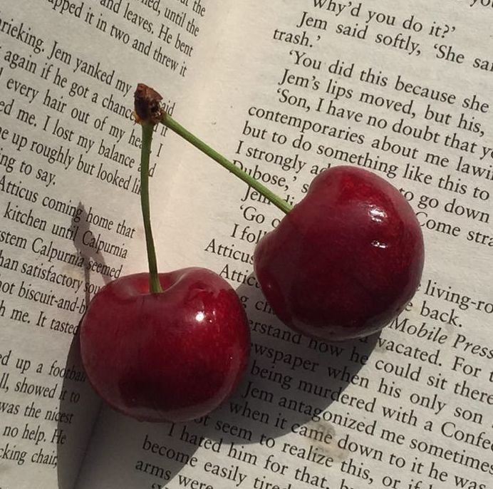 two cherries sitting on top of an open book