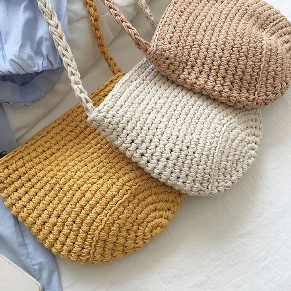 three different types of handbags hanging from clothes hangers on a white tablecloth