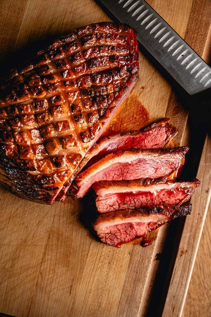 a large piece of meat sitting on top of a cutting board next to a knife