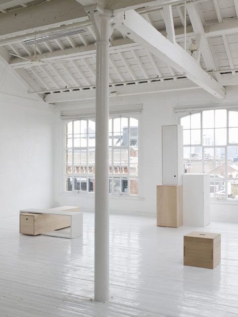 an empty room with white walls and wooden boxes on the floor in front of large windows