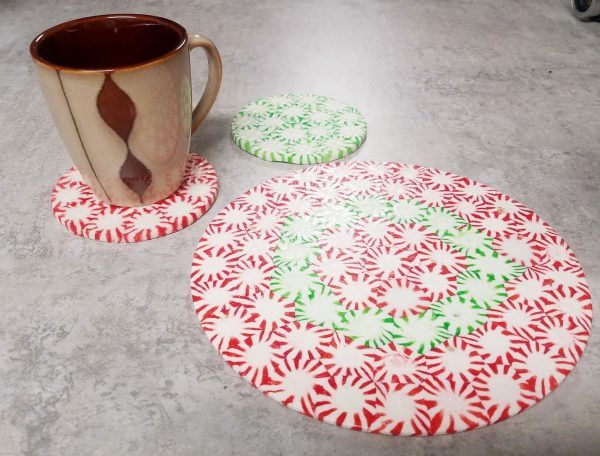 two coffee mugs sitting on top of a table next to coasters that have snowflakes on them