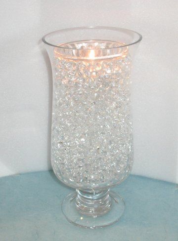 a clear glass vase filled with lots of sparkles on top of a blue table