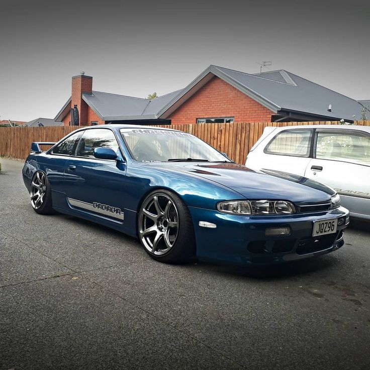 a blue car parked next to two white cars