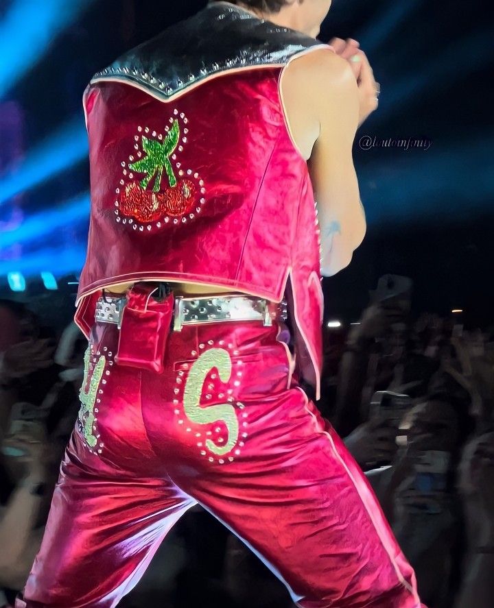 the man is dressed in red and has his hands on his hips as he performs