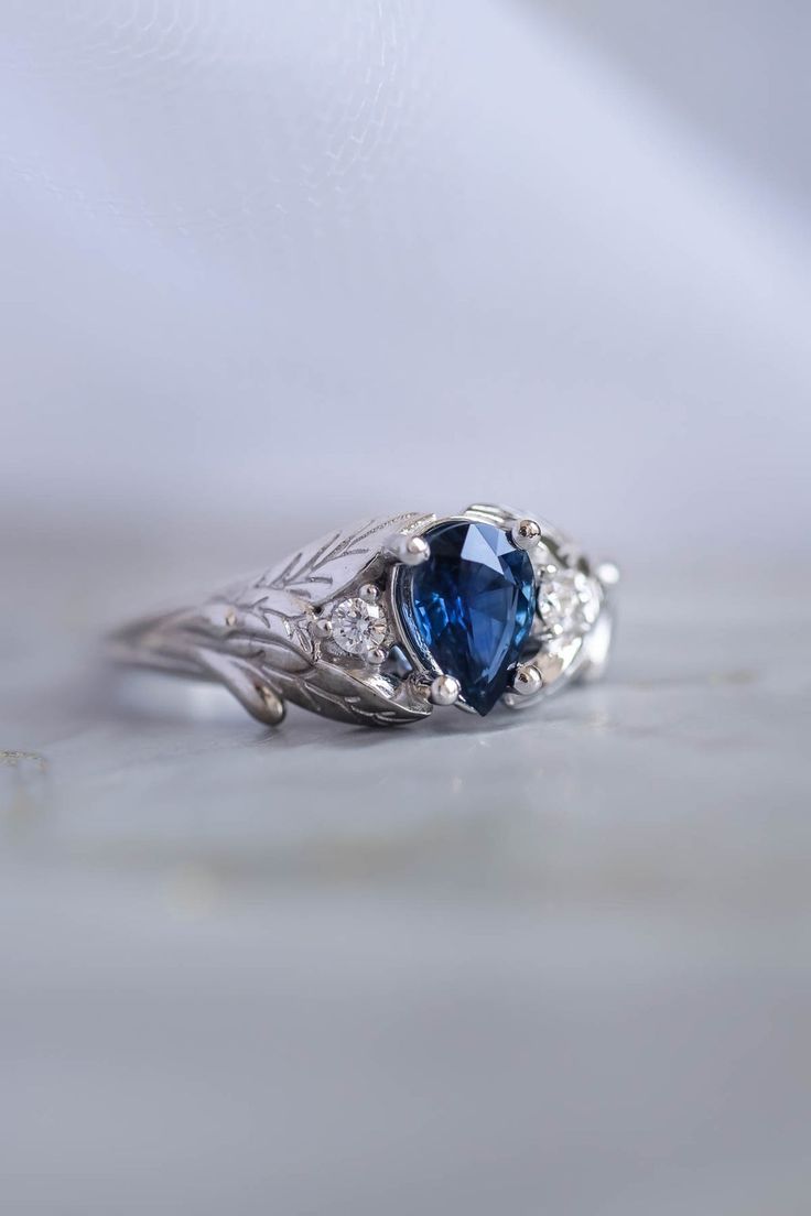 a close up view of a ring with a blue stone in the center and diamond accents