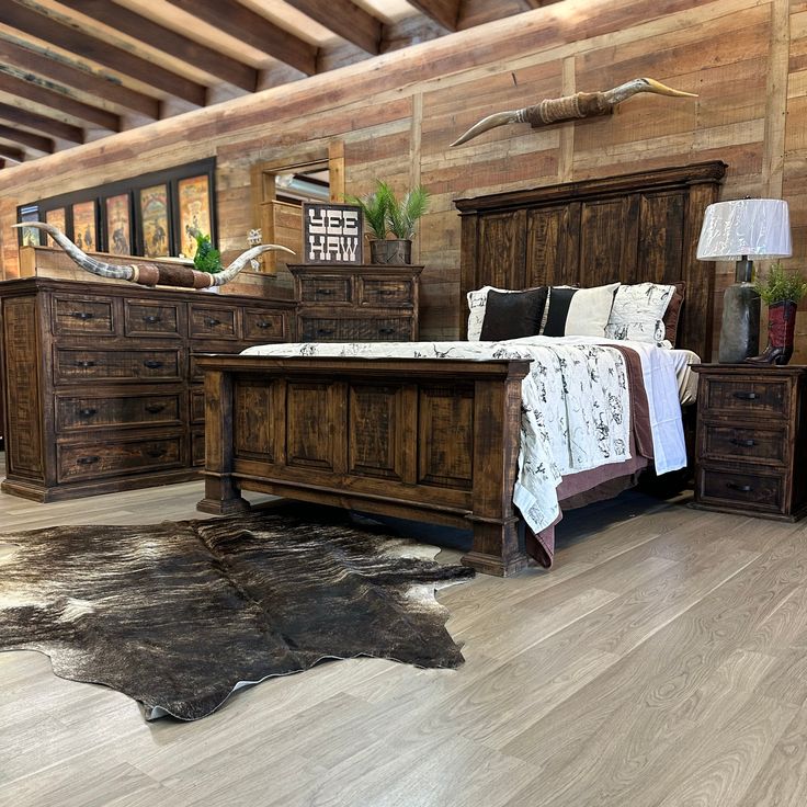 a bed room with a neatly made bed and wooden furniture on the floor next to a cowhide rug