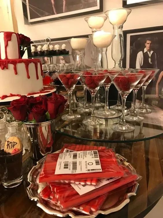 a table topped with lots of glasses filled with red liquid and covered in white frosting