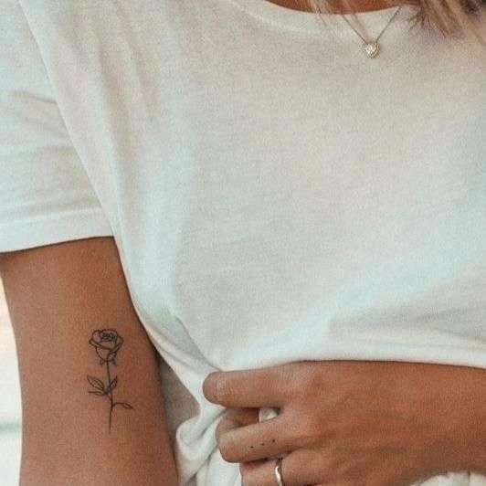 a woman with a small rose tattoo on her arm