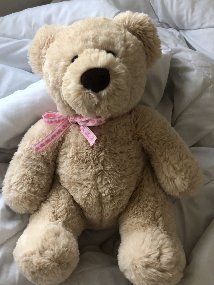 a brown teddy bear sitting on top of a bed