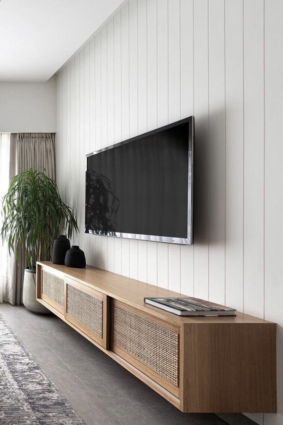 a flat screen tv mounted to the side of a wall next to a potted plant