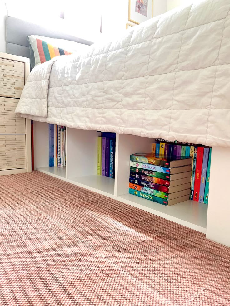 a bed that has some books on top of it and is next to a dresser