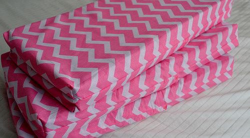 three pink and white chevroned sheets folded on top of each other in the shape of zigzag