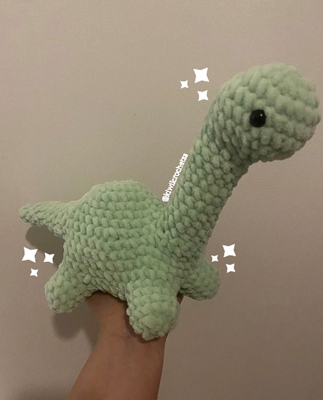 a hand holding a green stuffed animal with white stars on the wall in the background