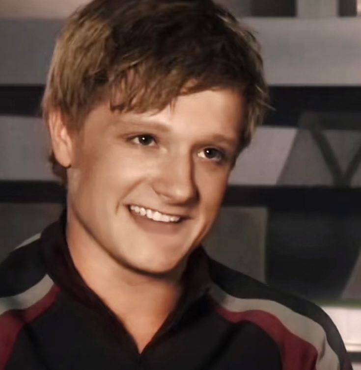 a close up of a person wearing a black and red shirt smiling at the camera