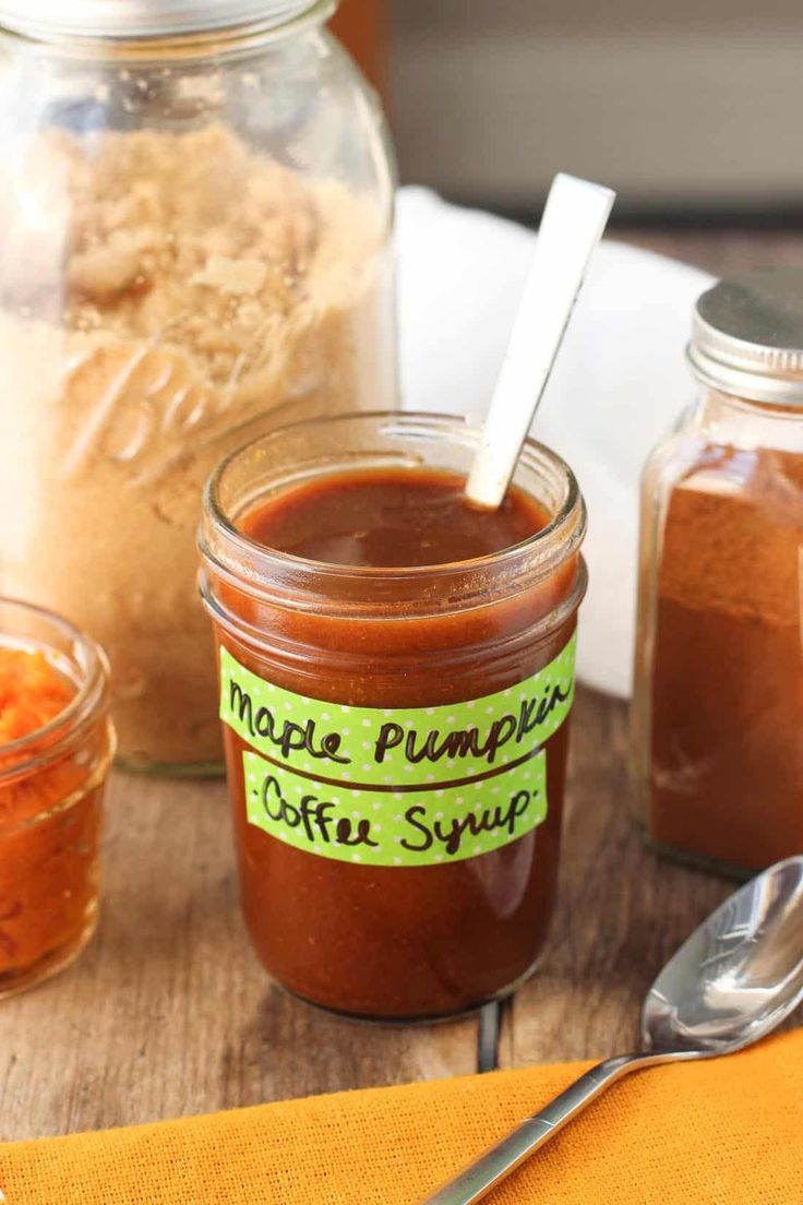 there are several jars with different types of sauces in them and spoons on the table