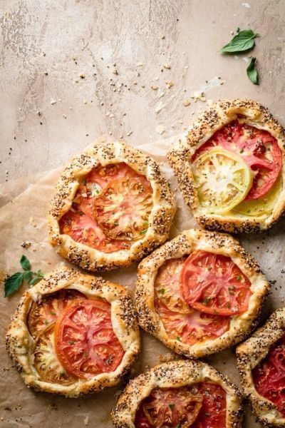 several small pies with tomatoes and herbs on top