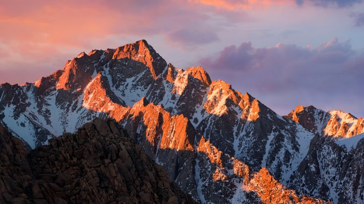 the mountain is covered in snow and has some pink light on it's top