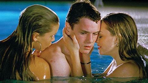 three people are in the water and one is holding his head to his ear as he kisses the other woman's cheek