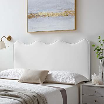 a white bed sitting in a bedroom next to a painting