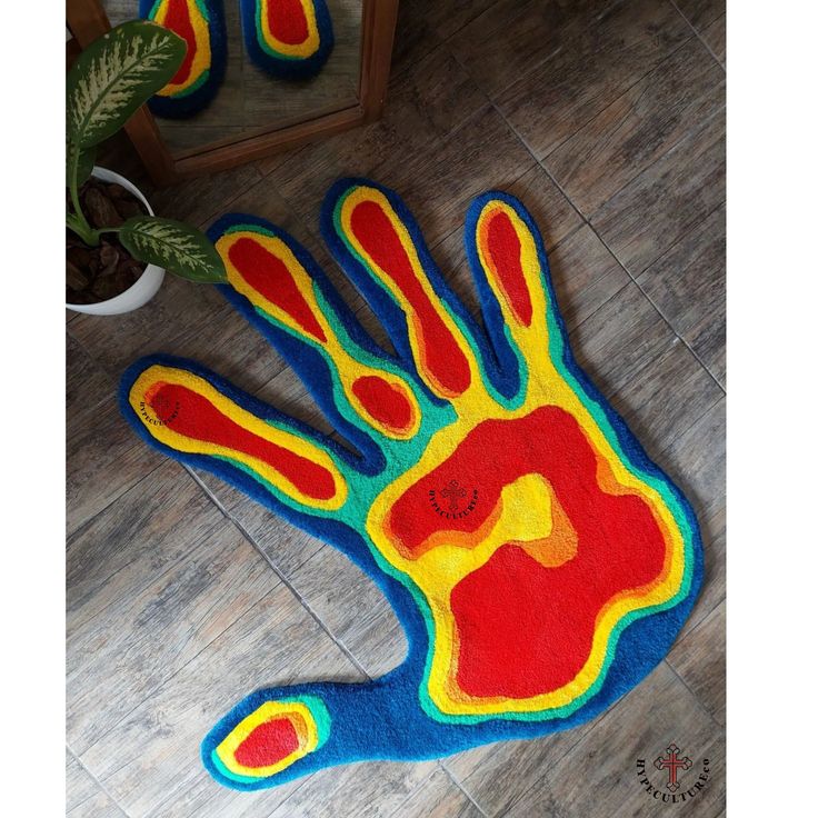 a colorful hand rug is on the floor next to a potted plant and mirror