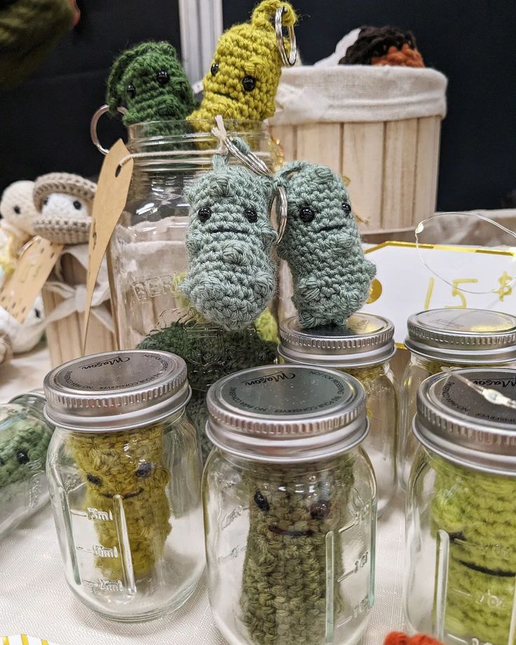 crocheted stuffed animals are in jars on a table with other knitted items