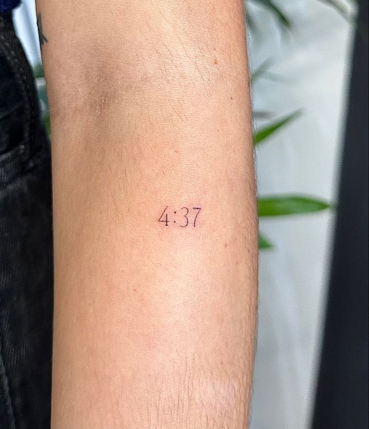 a person with a small tattoo on their arm that says 437 in pink ink