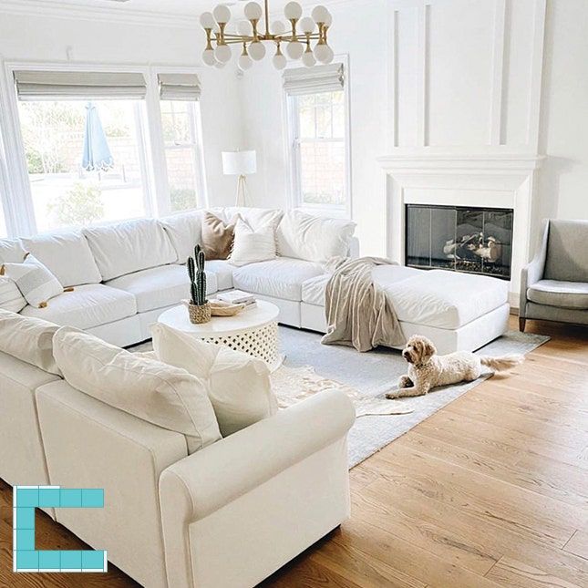 a living room filled with white furniture and a fire place in the middle of it