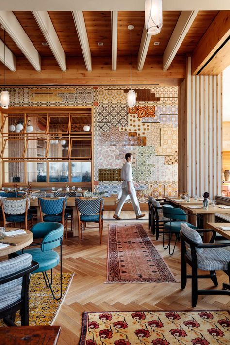 a person walking through a restaurant with lots of tables and chairs