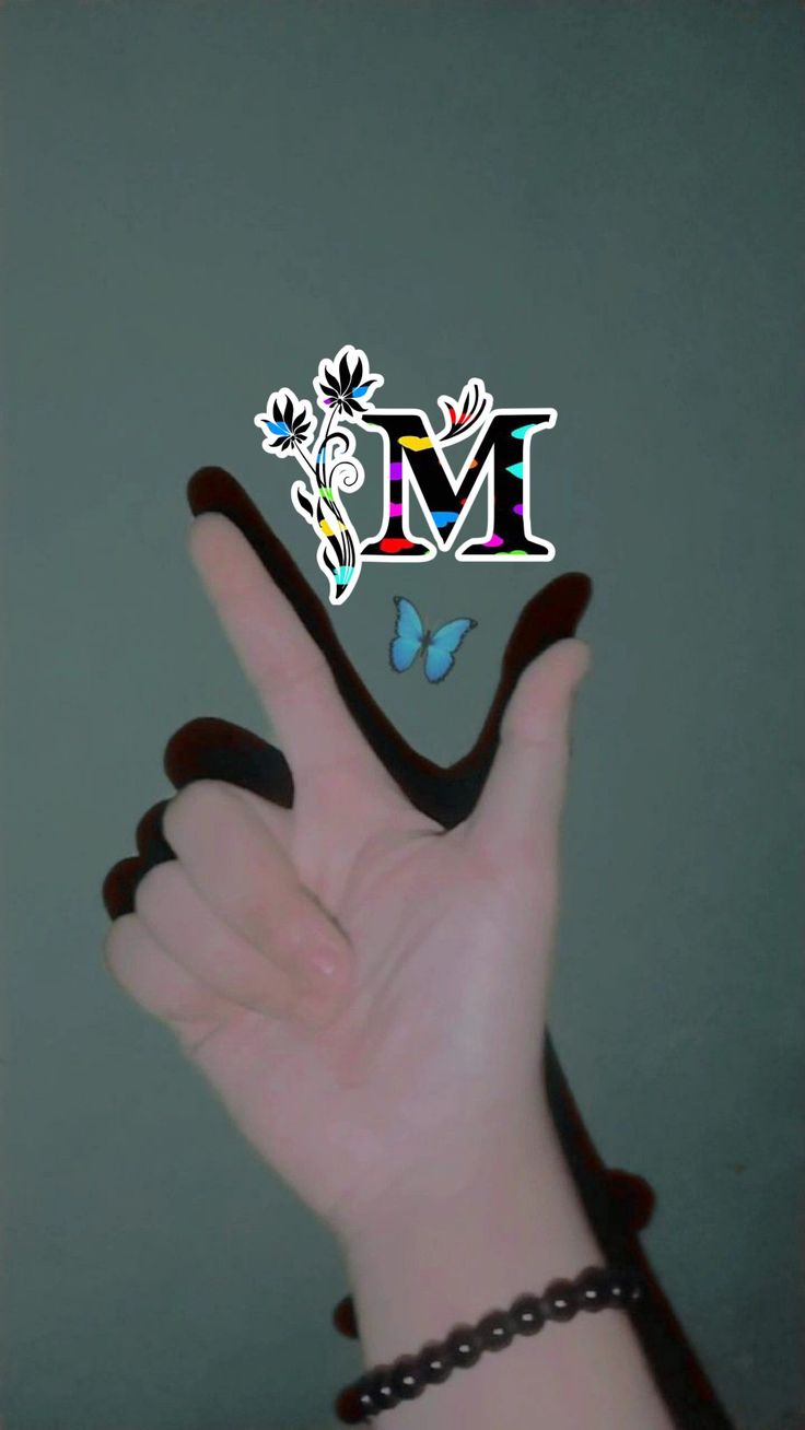 a person's hand with the letter m on it and a butterfly flying over them