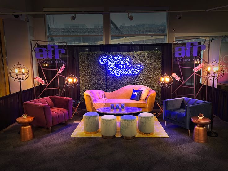 a living room with couches, chairs and tables in front of a neon sign